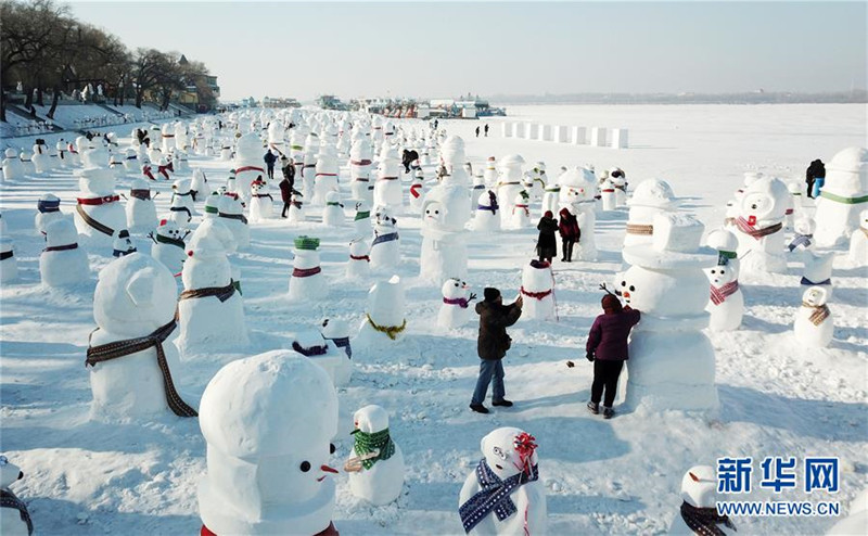 1月2日，市民、游客在雪人群中游玩觀賞（無人機(jī)拍攝）。2019個(gè)各式各樣的雪人，近日在冰城哈爾濱市的松花江畔亮相，引來眾多市民游客游玩觀賞。新華社記者 王建威 攝